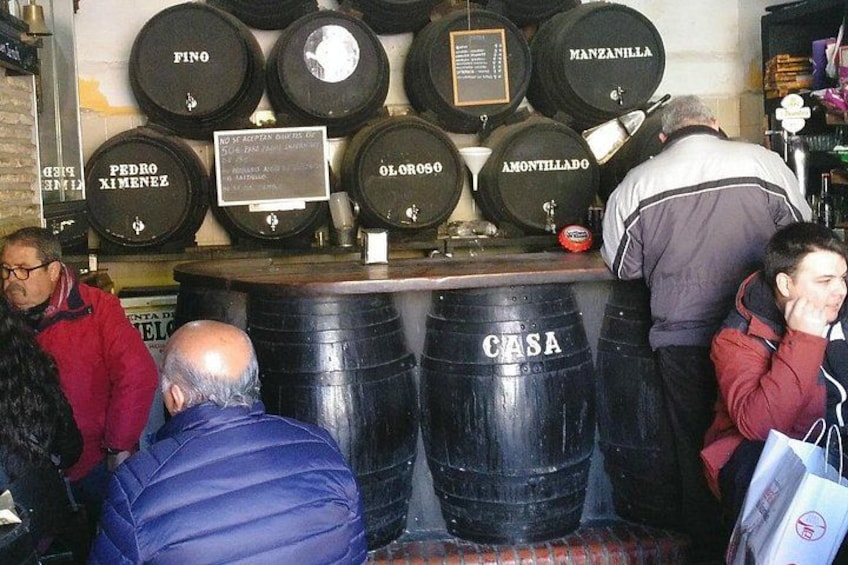 A bar with large black barrels labeled with names like 'PEDRO XIMENEZ' and 'MANZANILLA.' 2