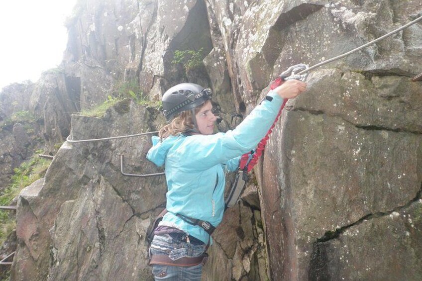A person climbing a rocky cliff with a harness and helmet. 2