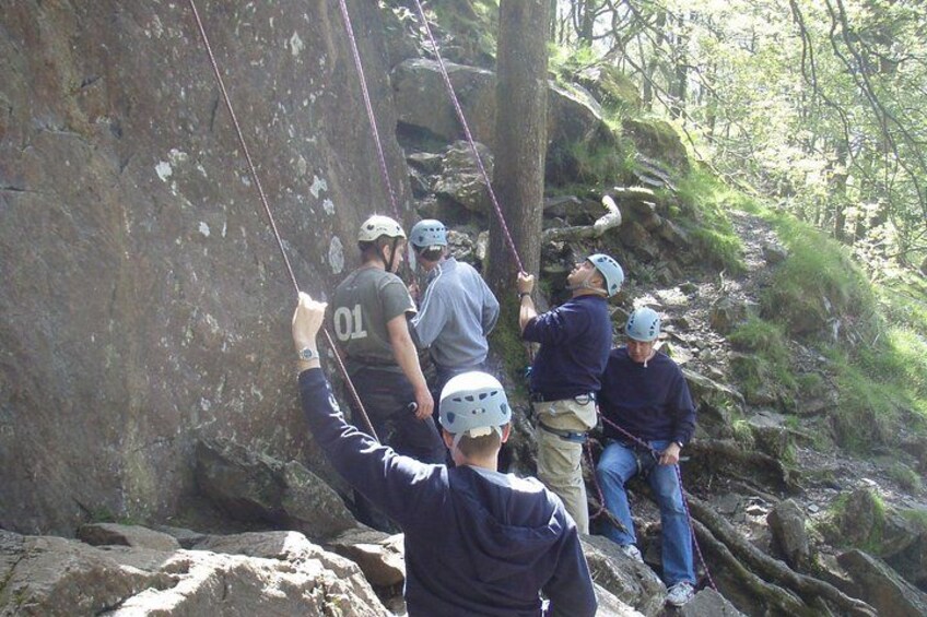 Eine Gruppe von Menschen klettert an einer Felswand, dabei werden Seile und Gurte verwendet. 2