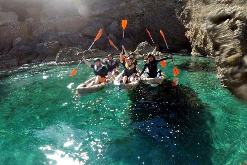 Un grupo de personas haciendo kayak en aguas cristalinas con acantilados rocosos al fondo. 3