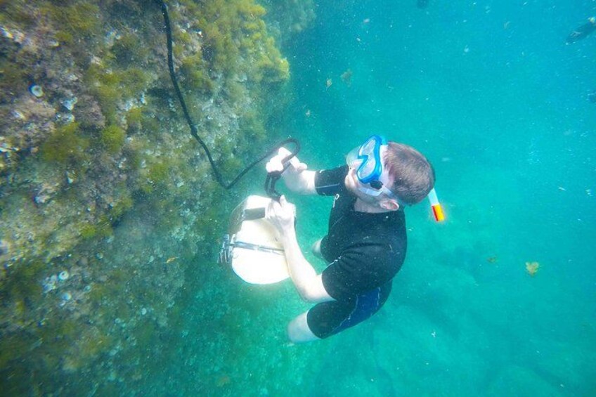 Una persona practica snorkel bajo el agua, usando un tubo de snorkel y máscara, con una cámara sobre un trípode. 2