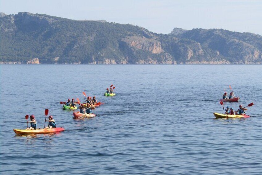 Un groupe de personnes pratiquant le kayak sur une étendue d’eau calme, avec des collines en arrière-plan. 3