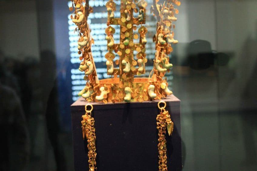 A display of intricate gold jewelry with a central structure and hanging elements. 5