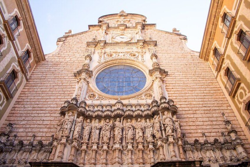 Une façade richement décorée d’un bâtiment historique, ornée de sculptures complexes et dotée d’une grande fenêtre circulaire. 3