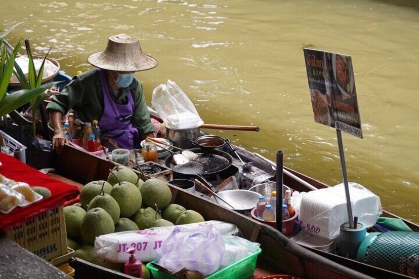 A floating market with vendors selling fruits and cooking equipment. 5