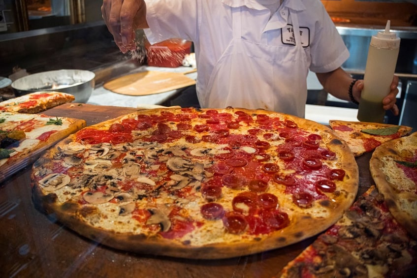 Een pizzeria met een grote pizza belegd met pepperoni en champignons. 1