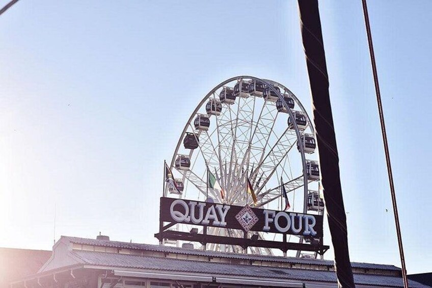 A Ferris wheel with the sign 'Quay Four' in front of a building. 3