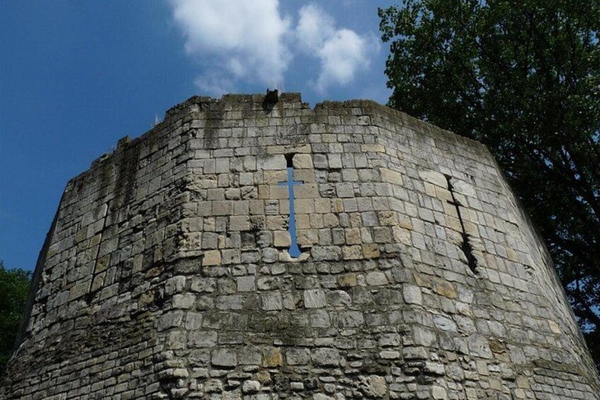 Een stenen toren met een blauw kruis aan de zijkant. 4