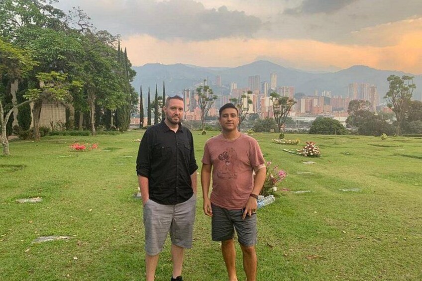 Two people standing in a grassy field with a cityscape in the background. 5
