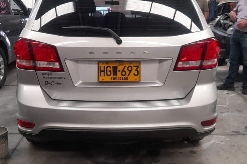 A silver car with a yellow license plate in a garage. 5