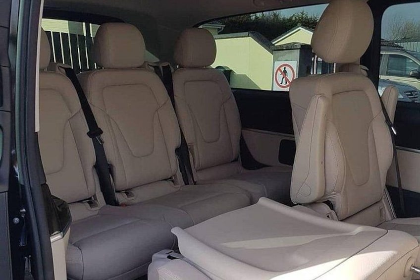 A car interior with beige leather seats and a sunroof. 4