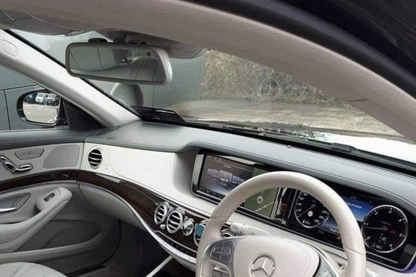 A luxury car interior with a steering wheel, dashboard, and center console. 3