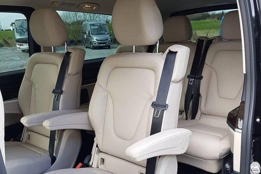 A car's interior with beige leather seats and a sunroof. 5