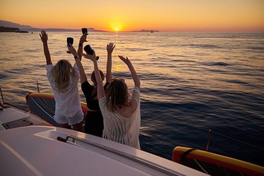 A sunset over the ocean with people on a boat raising their hands. 5