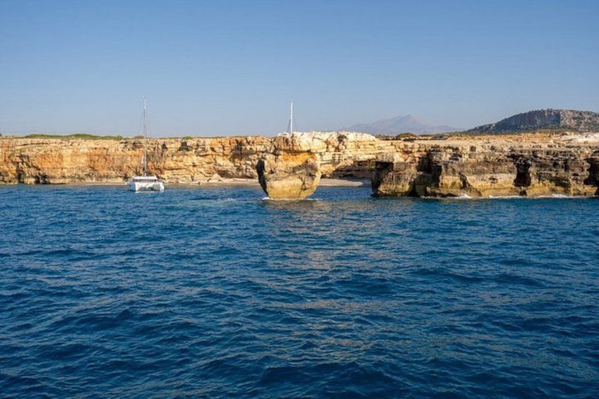 Una costa rocosa con un puente, un barco y una montaña distante. 2