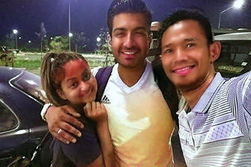 Tres personas de pie juntas frente a un automóvil de noche. 5