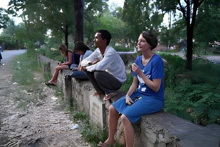 Personas sentadas sobre un muro de concreto al lado de un sendero de tierra en un parque. 2