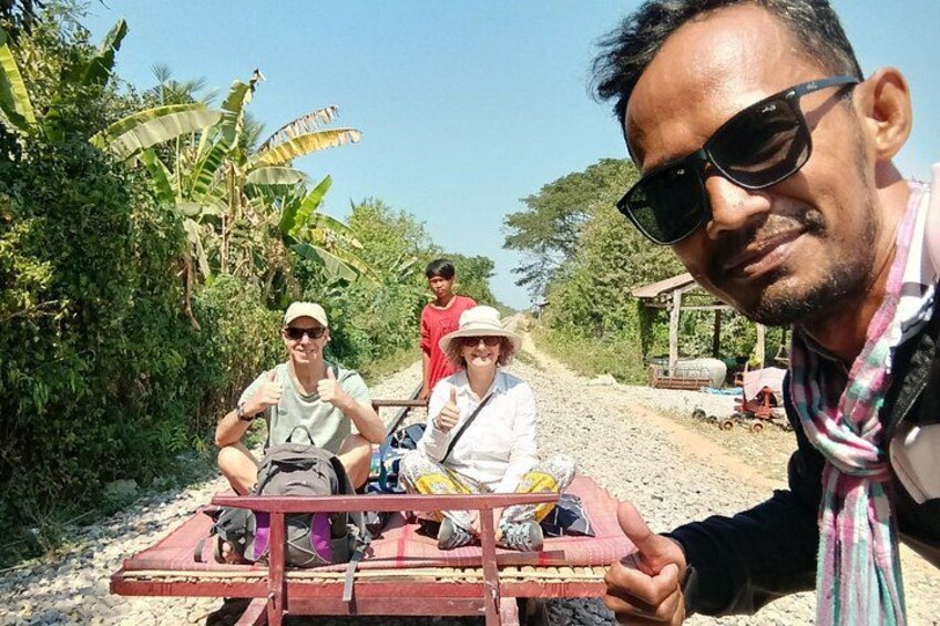 A group of people on a small vehicle, a rural road, and vegetation. 4