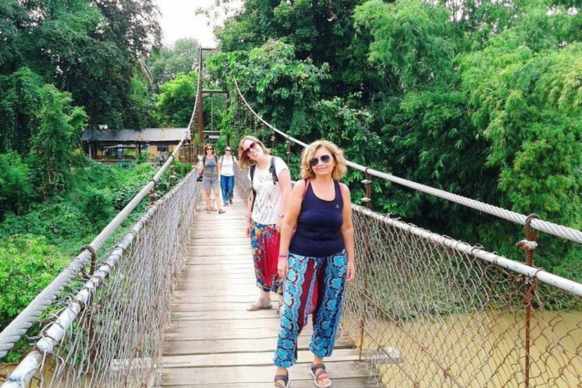 A suspension bridge in a forested area with people walking on it. 2