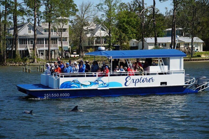 A boat named 'Explorer' with people on board, surrounded by water and houses in the background. 2