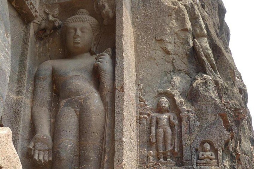 A large stone statue of a seated figure with a smaller figure beside it, both carved into a rock face. 4