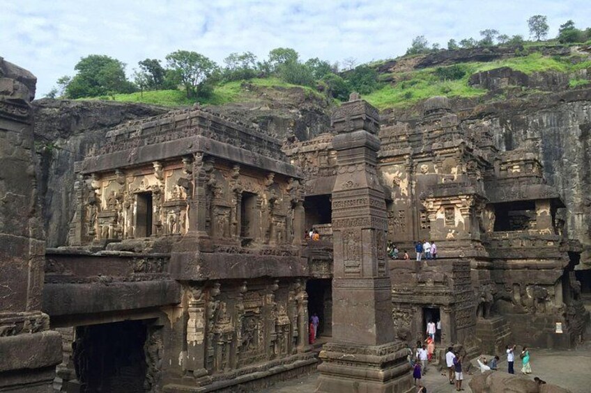 Ancient rock-cut architecture with intricate carvings and a group of people observing. 2