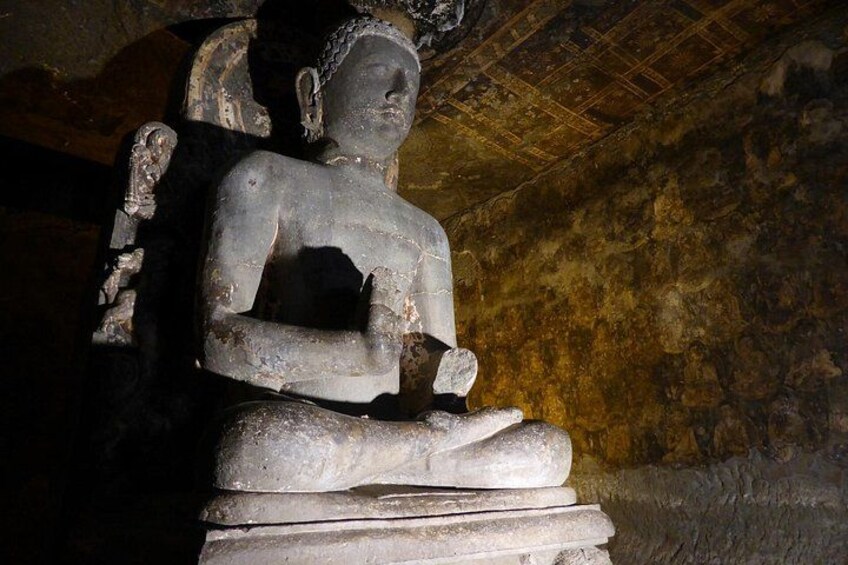 A stone statue of a seated figure in a cave. 2