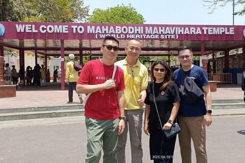 Een groep mensen staat voor een bord met de tekst 'WELCOME TO MAHABODHI MAHAVIHARA TEMPLE (WORLD HERITAGE SITE)'. 5