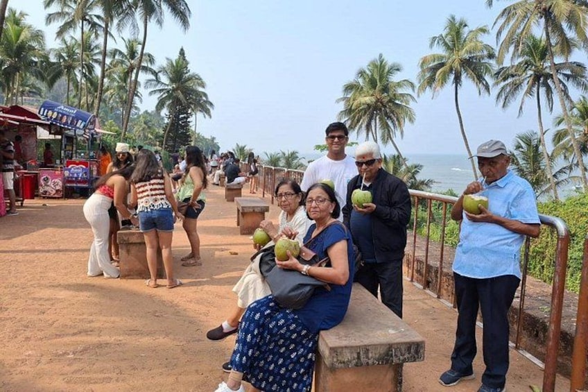 A group of people sitting and standing on a concrete platform with palm trees and the ocean in the background. 5
