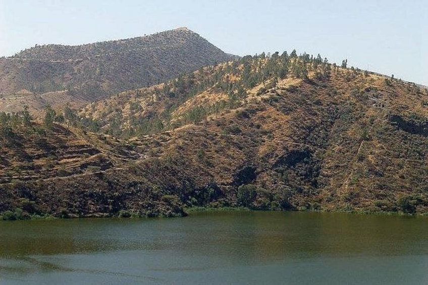 A hilly landscape with a body of water in the foreground. 1