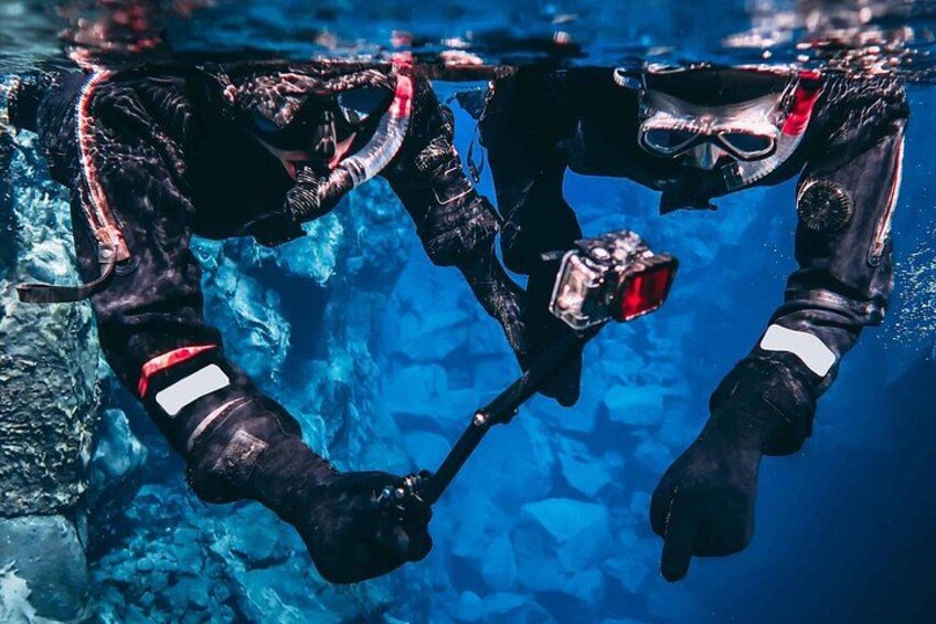 A diver in a black wetsuit with red and white markings, using a scuba regulator underwater. 2