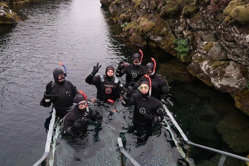 A group of divers in black wetsuits and helmets on a boat in a river. 3