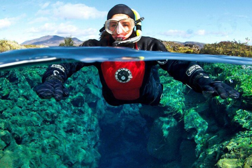 A person scuba diving in clear blue water with rocky underwater terrain. 3