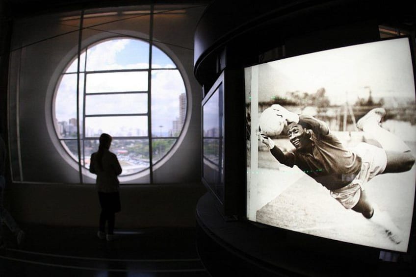 A person standing in front of a large circular window with a cityscape view. 2