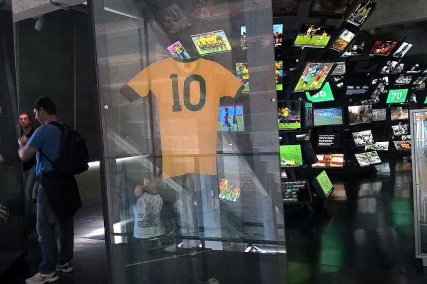 A sports museum with a glass display case featuring a yellow jersey with the number 10. 4