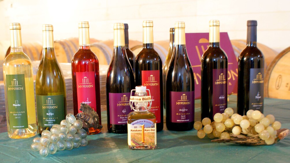 A variety of wine bottles and grapes on a table. 2