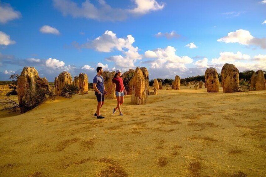 Two people standing in a desert landscape with large rock formations in the background. 5