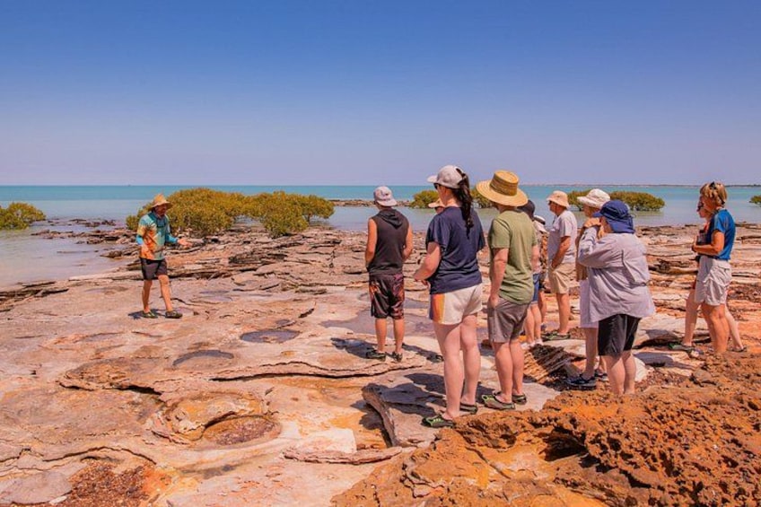 A group of people standing on rocky terrain near a body of water. 5