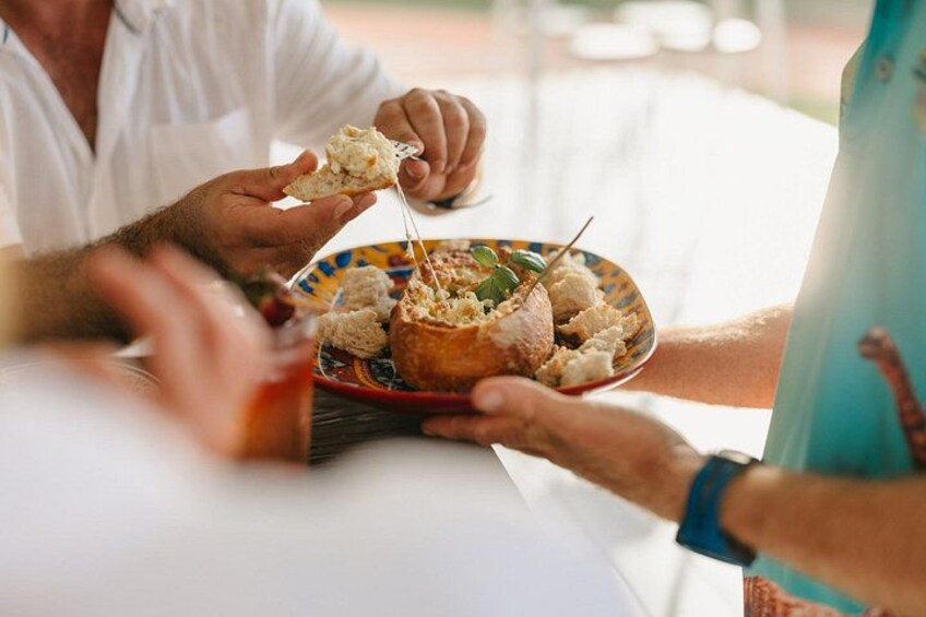 A person holding a plate with food, another person reaching for it, and a table with a drink. 4