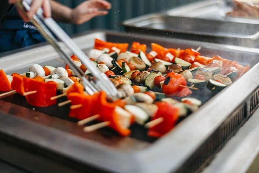 A grill with skewered vegetables and mushrooms being cooked. 5