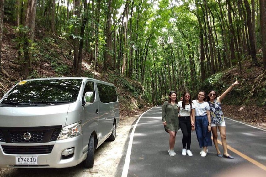 Una camioneta plateada estacionada en un camino forestal, con cuatro personas de pie a su lado. 2