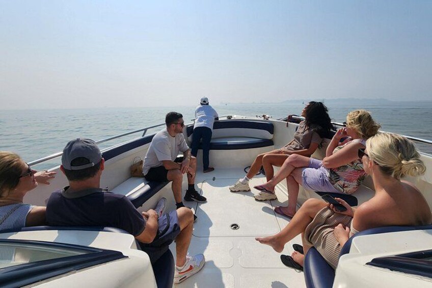 A group of people on a boat with a calm sea and distant land in the background. 1