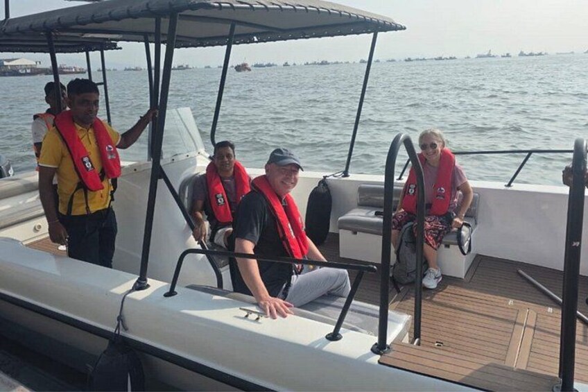 A boat with people wearing life jackets, a wooden deck, and a body of water in the background. 3