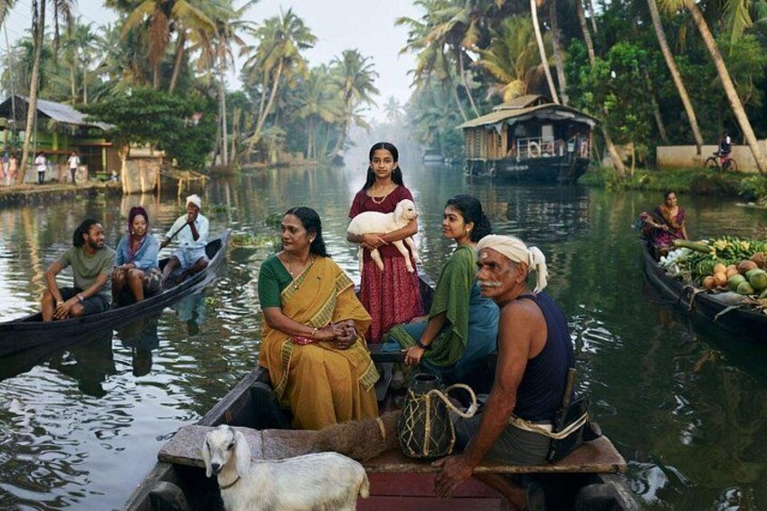 A group of people in a boat on a river with palm trees and houses in the background. 5