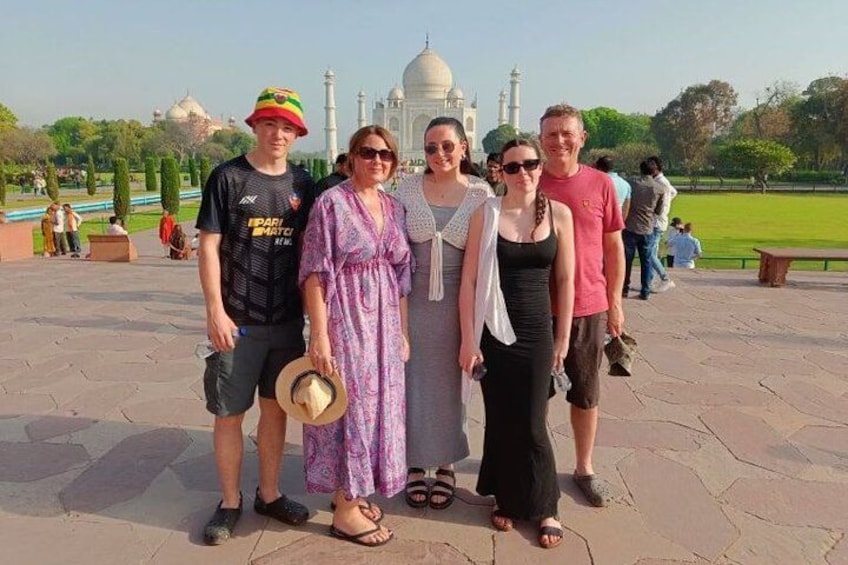 A group of people standing in front of a large white dome structure with a reflection in the water. 1