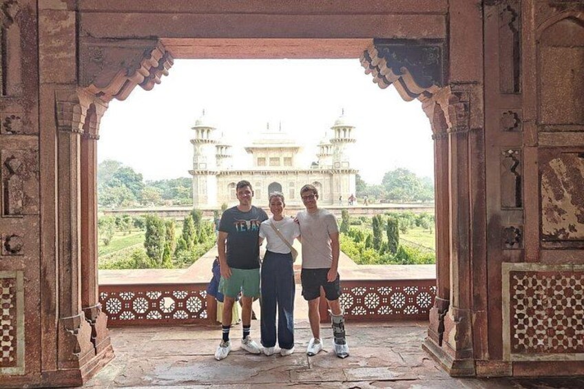 A group of people standing in an ornate doorway with a view of a large, white, multi-domed building in the background. 2