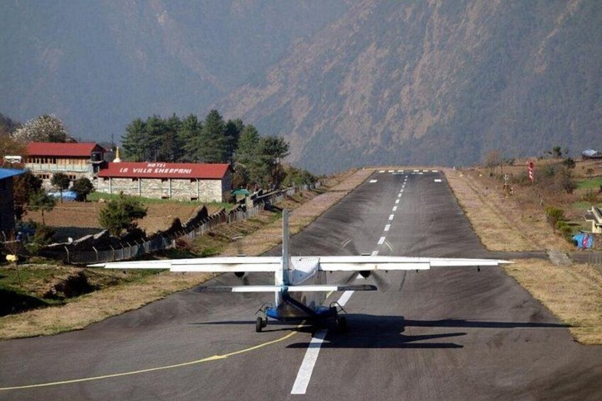 Un pequeño avión en una pista de aterrizaje, con montañas al fondo. 2