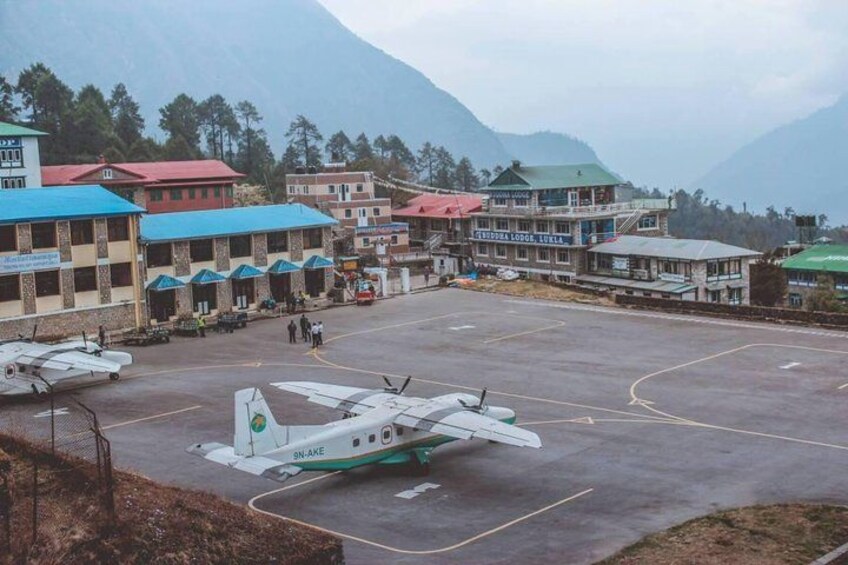 A small airport with a single airplane parked on the tarmac, surrounded by buildings with colorful roofs. 3
