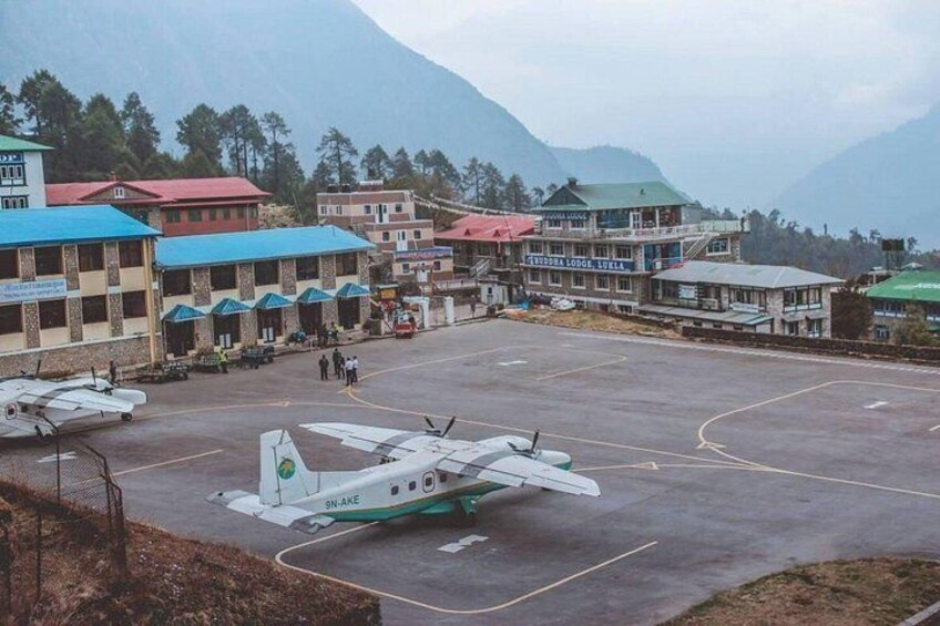Un aeropuerto pequeño con un solo avión estacionado en la plataforma, rodeado de edificios con techos de colores. 2