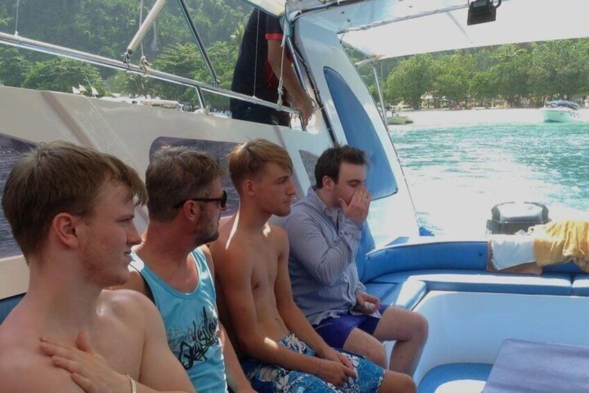 Four people on a boat with a tropical landscape in the background. 3